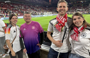 2 Mitglieder und deren Begleitung vor dem Spielfeld des RheinEnergie-Stadions in Köln
